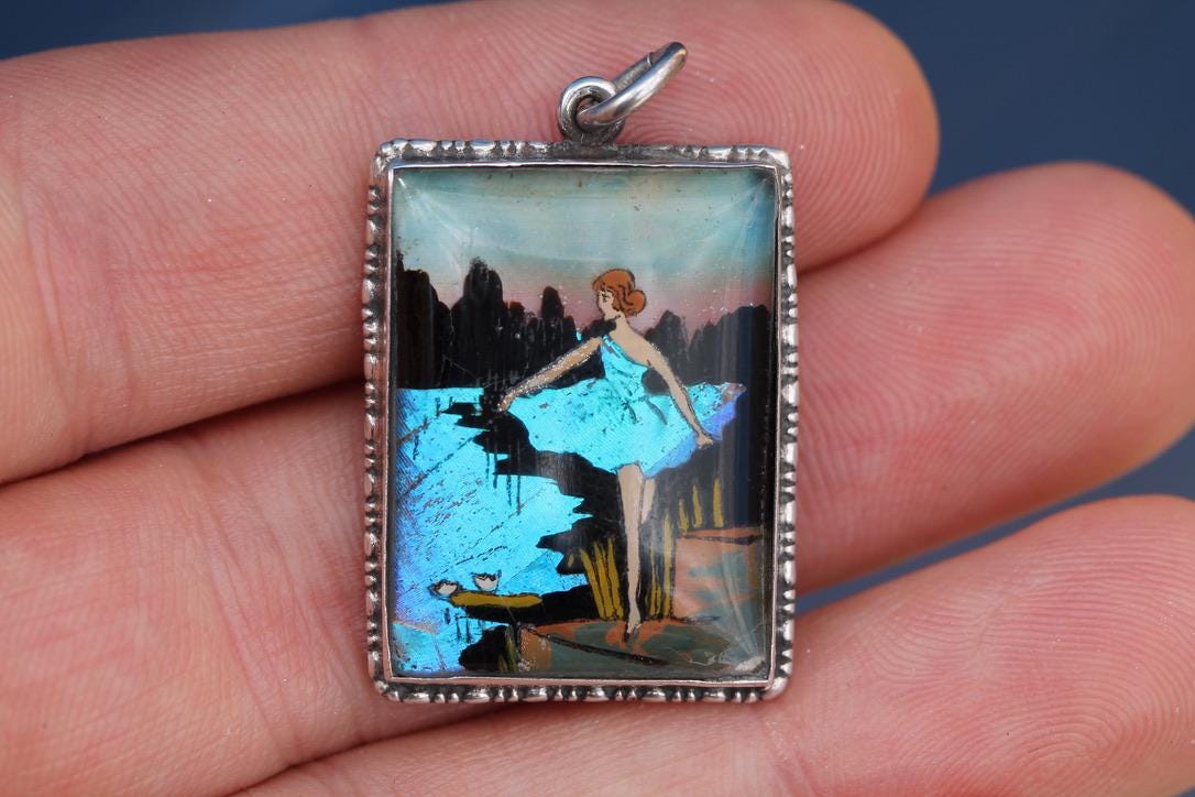 Art Deco sterling silver butterfly wing pendant depicting a lady beside blue water