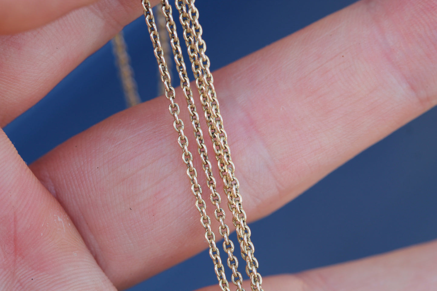 Close-up of 14ct gold chain showing small faceted sapphire cluster stations