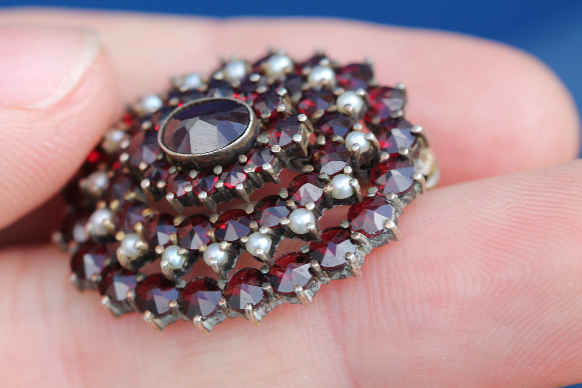 Side view of domed garnet and seed pearl cluster brooch