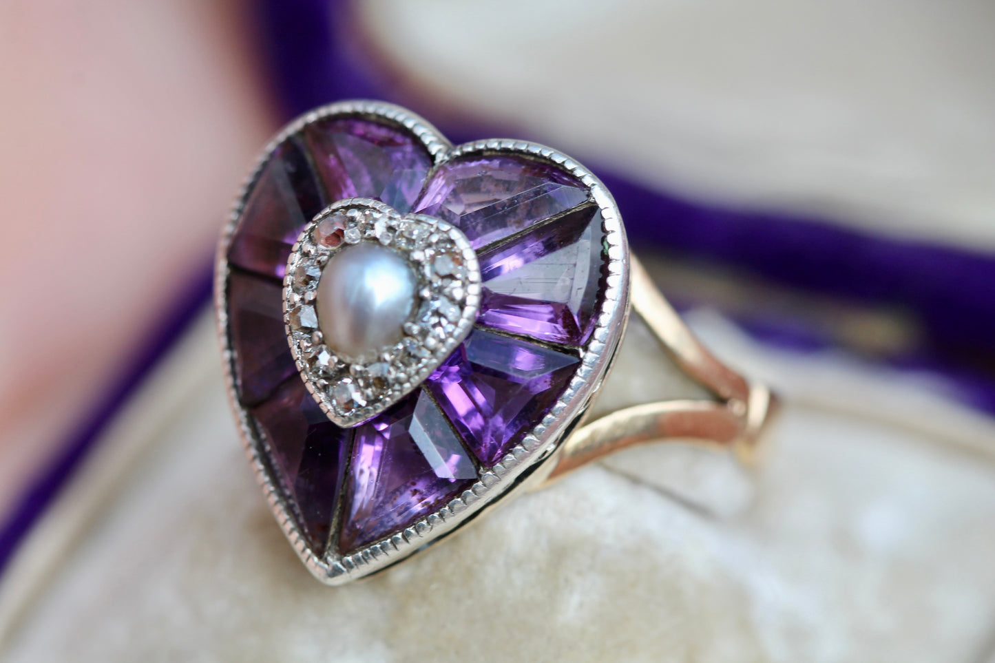 Close-up of silver-set amethyst heart ring with pearl and diamond centre