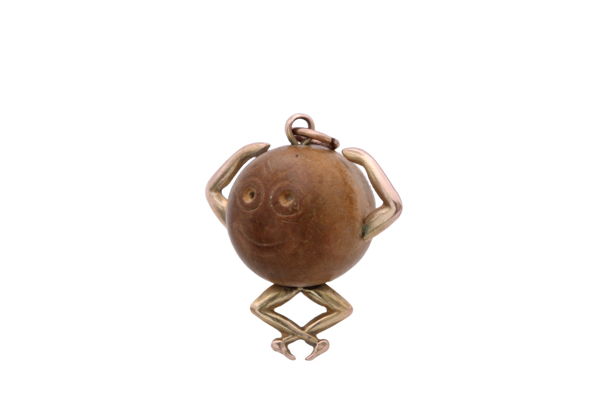 Close-up of antique Touch Wud charm showing face and articulated gold limbs