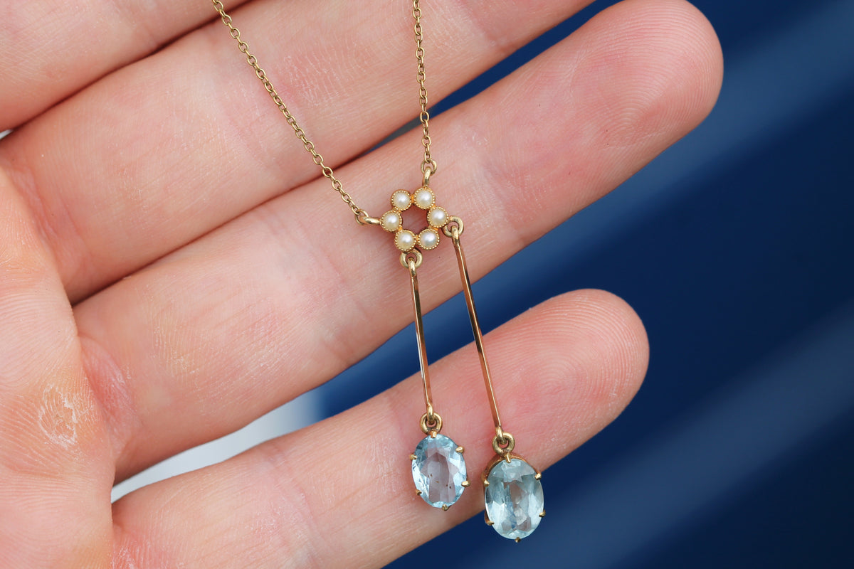 Close-up of twin oval aquamarines on asymmetric gold drops