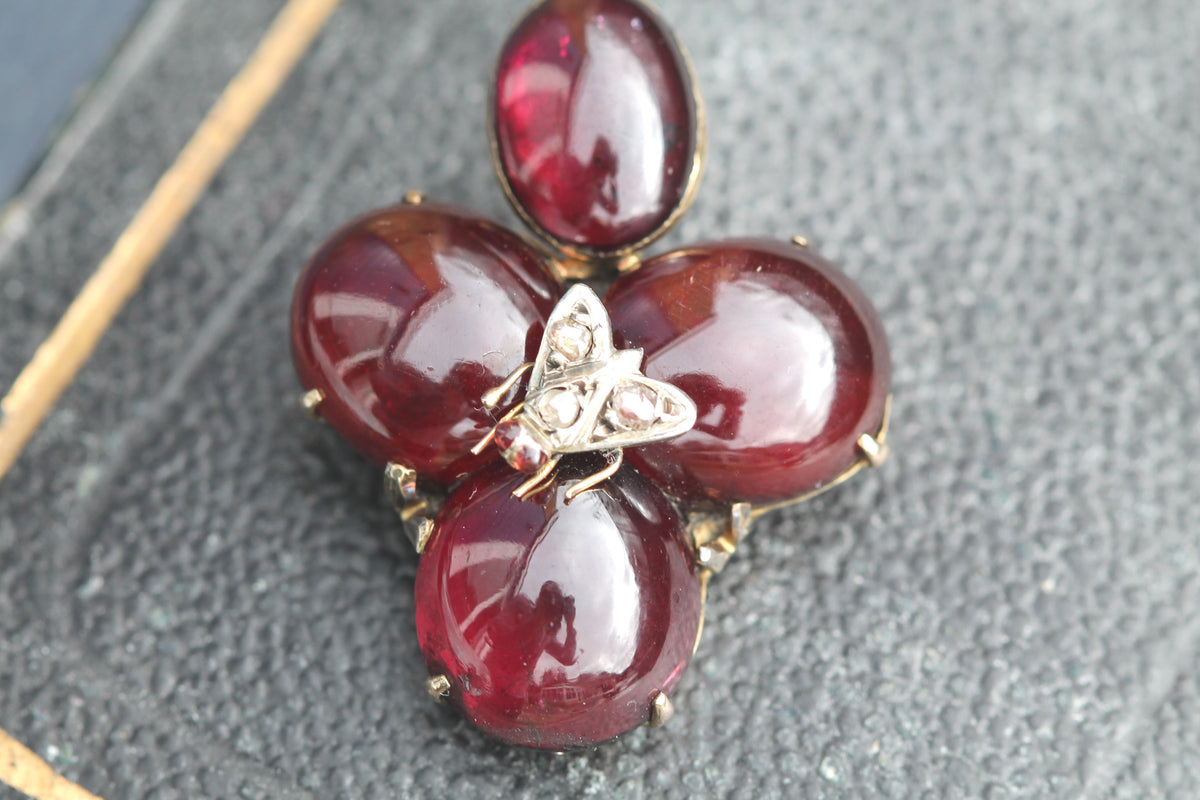 Victorian garnet flower pendant shown in the hand