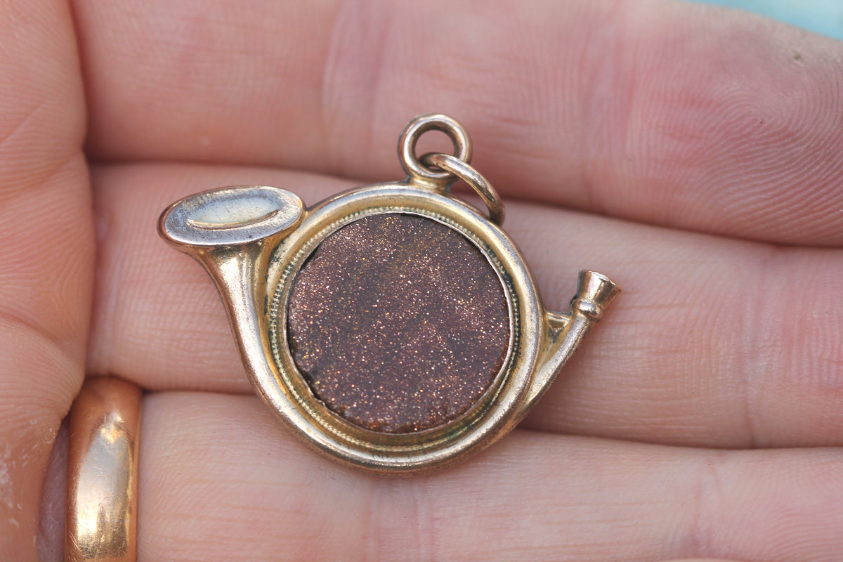 Antique rolled gold hunting horn and dog fob shown in the hand