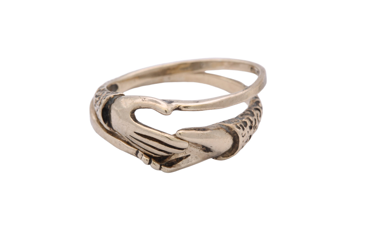 Interlocking fede rings joined together to form clasped hands