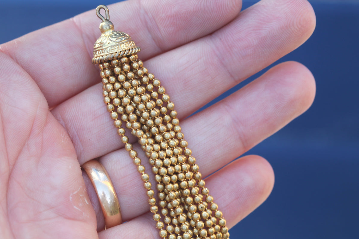 Large antique rolled gold tassel pendant shown in the hand