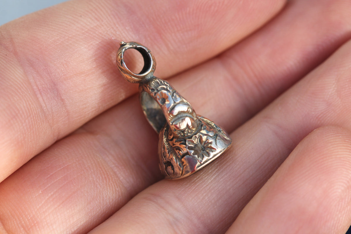 Antique tortoise intaglio seal held in hand showing ornate suspension