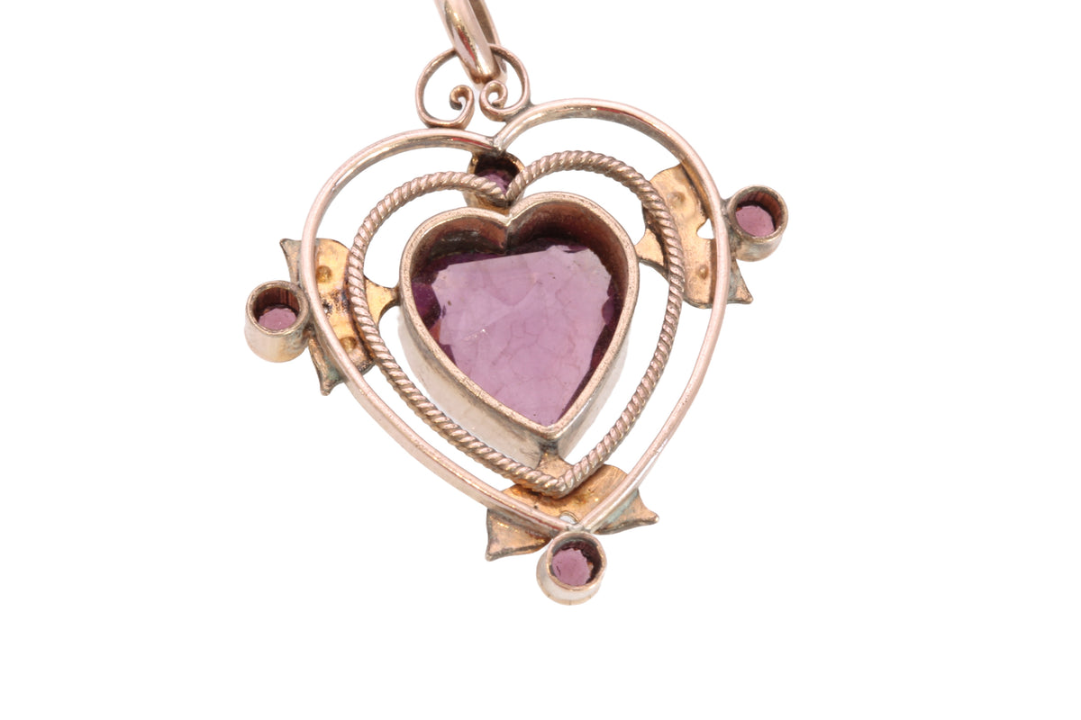 Side view of antique purple glass heart pendant with openwork setting