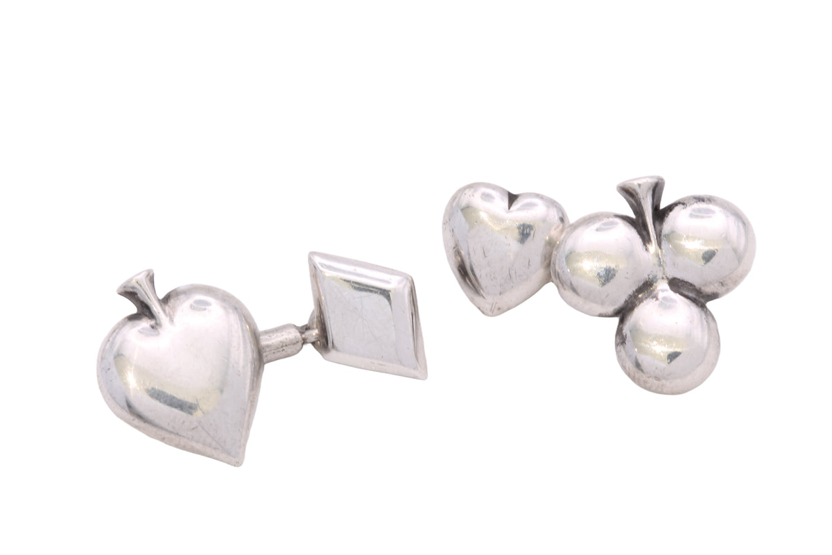 Sterling silver card suit cufflinks held in hand showing sculptural polished forms