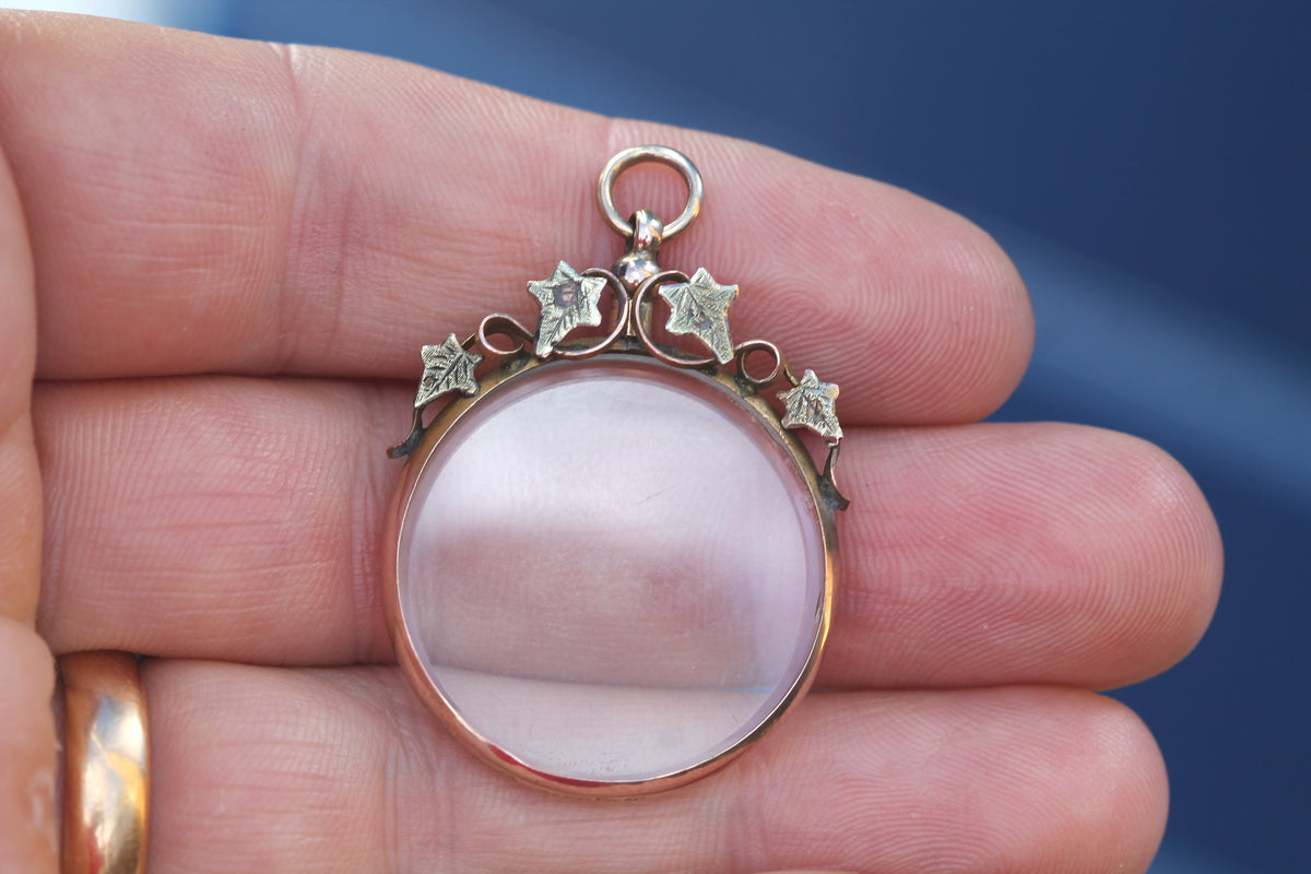 Edwardian ivy glass locket held in hand showing green gold leaves